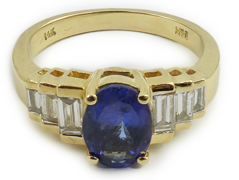 A modern 14k gold and single stone oval cut tanzanite set dress ring, with six stone graduated baguette cut diamond set shoulders